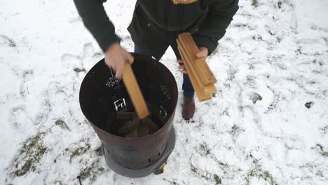 Man-Piling-Up-Wood-in-Outdoor-Fire-Barrel-Winter-Scenery