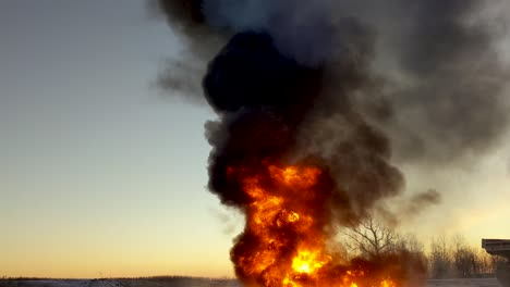 huge cloud of black smoke billows into the sky as an oil spill burns up on the ground below