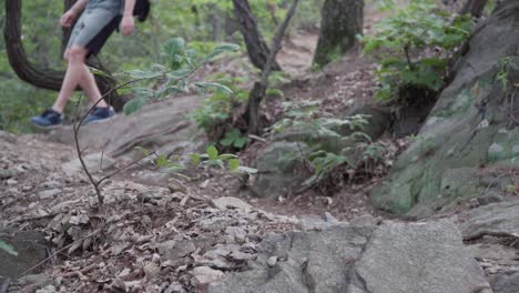 blurred legs of male hiker walking down a rocky mountain with narrow path - medium shot, hiking concept