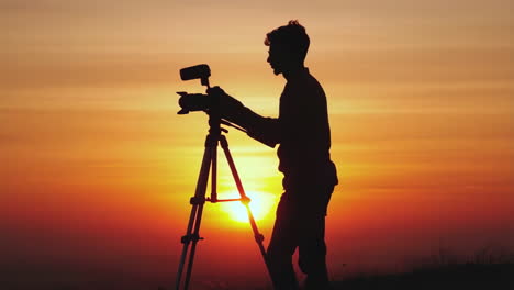 photographer silhouetted against a sunset
