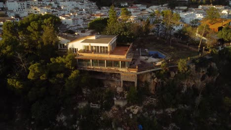 mansión de lujo en el lado del acantilado con el municipio de mijas en el fondo, vista aérea