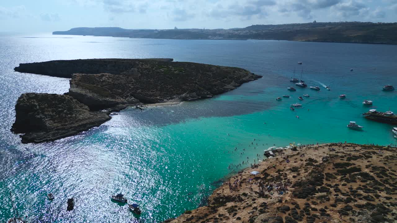 Aerial panoramic over Gozo rugged coast with turquoise water, rocky edges, and bright shoreline, Malta