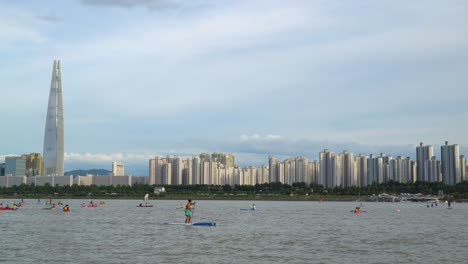 turista en deportes acuáticos recreativos en el río han con telón de fondo de lotte world tower en seúl, corea del sur