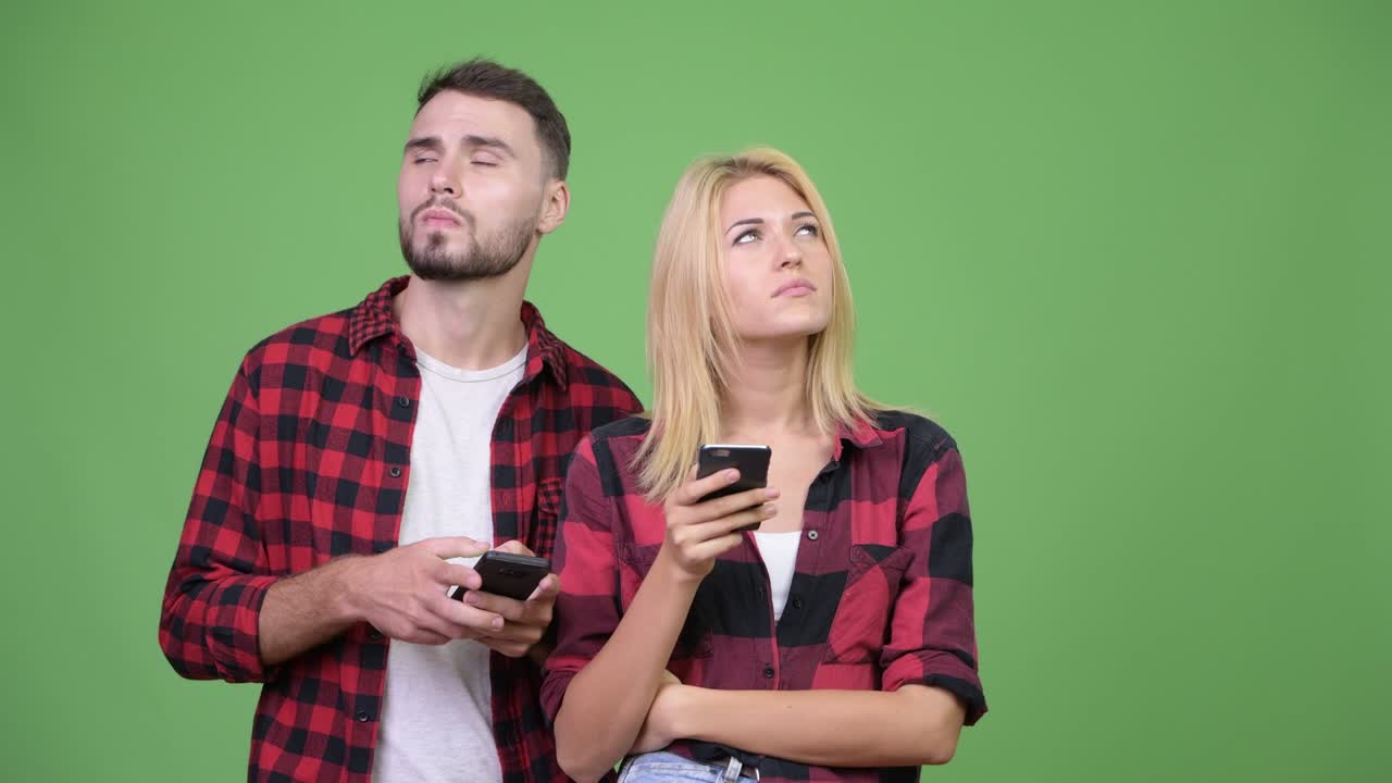 Young couple thinking while using phone together
