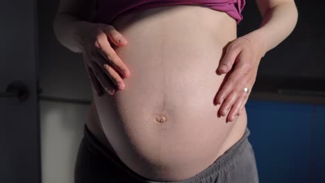 heavily pregnant caucasian woman holds stomach