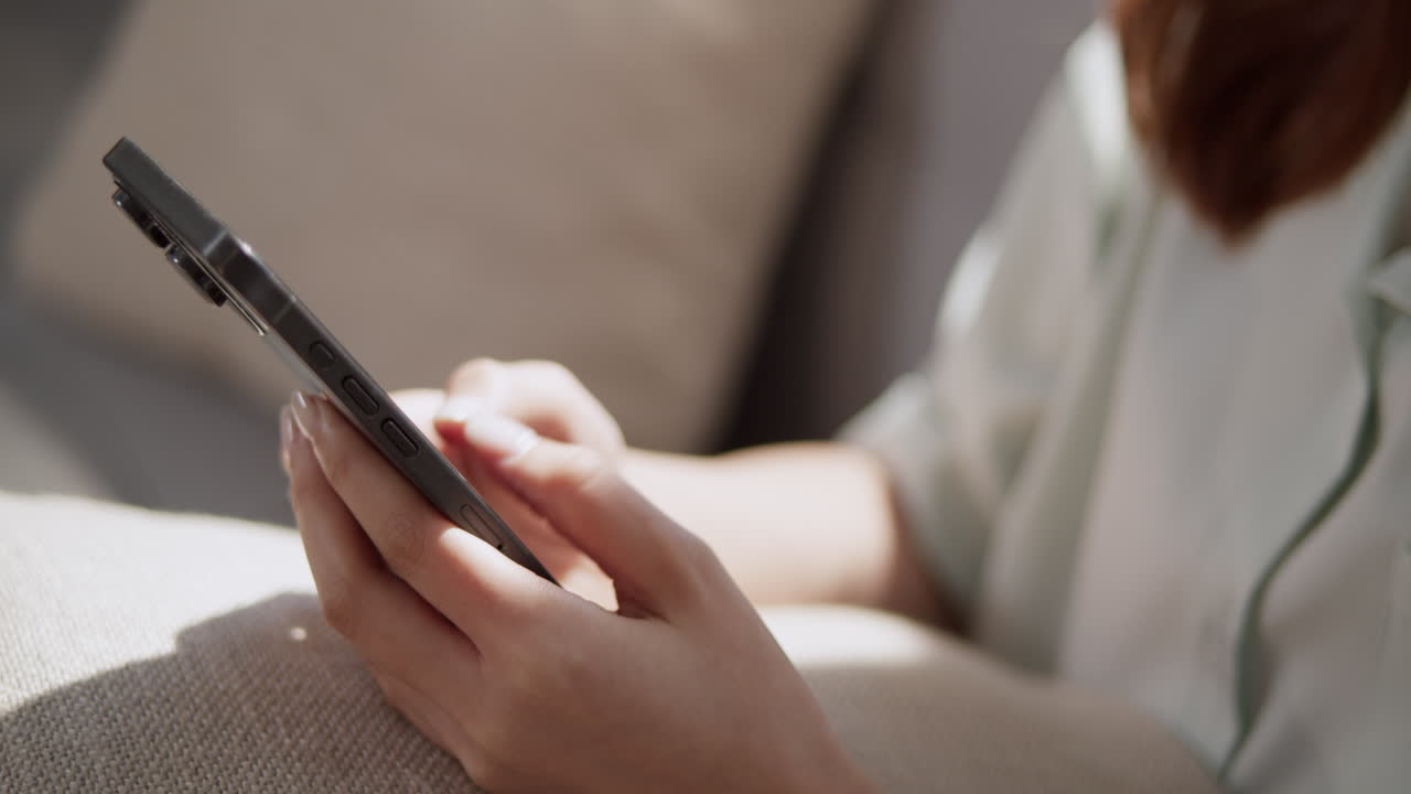 Panning from the right to left on a close-up shot of a woman who is chatting on social media using her mobile phone.