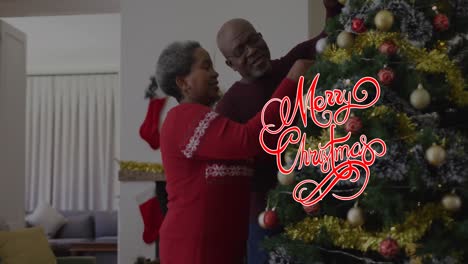 Animation-of-christmas-greetings-text-over-african-american-couple-decorating-christmas-tree