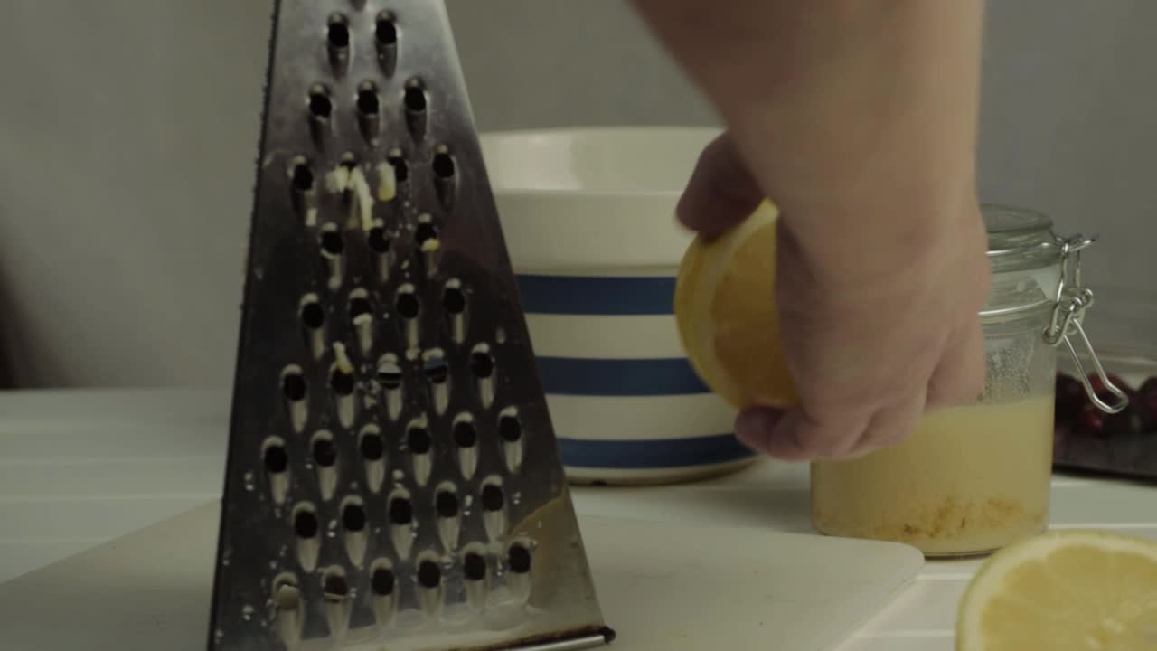 Grattugiando a mano un limone succoso in cucina con gli ingredienti