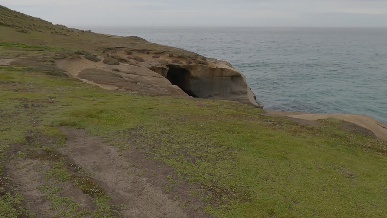 caminata lenta en el promontorio hacia el arco de roca natural - vía de la playa del túnel, dunedin