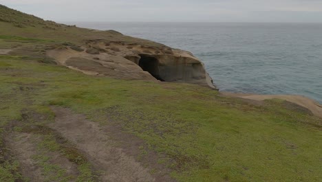 Slow-walk-on-headland-towards-natural-rock-archway---Tunnel-Beach-Track,-Dunedin