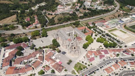 Cityscape-of-Batalha-and-majestic-monastery-complex-building,-aerial-descend-flying-toward-view