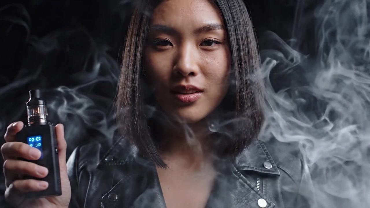 Tyylikäs henkilö esittelee virtaviivaista vape-laitetta tummaa taustaa vasten, päästäen savupilviä, korostaen höyryttelykulttuurin ja -elämäntavan moderneja trendejä.