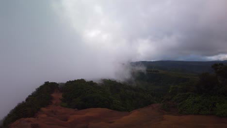 Gimbal-wide-panning-shot-of-the-thick-marine-layer-spilling-over-the-top-of-the-Na-Pali-mountains-in-Waimea-Canyon-on-the-island-of-Kaua'i,-Hawai'i