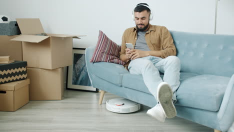 man relaxing on a sofa while robot vacuum cleans