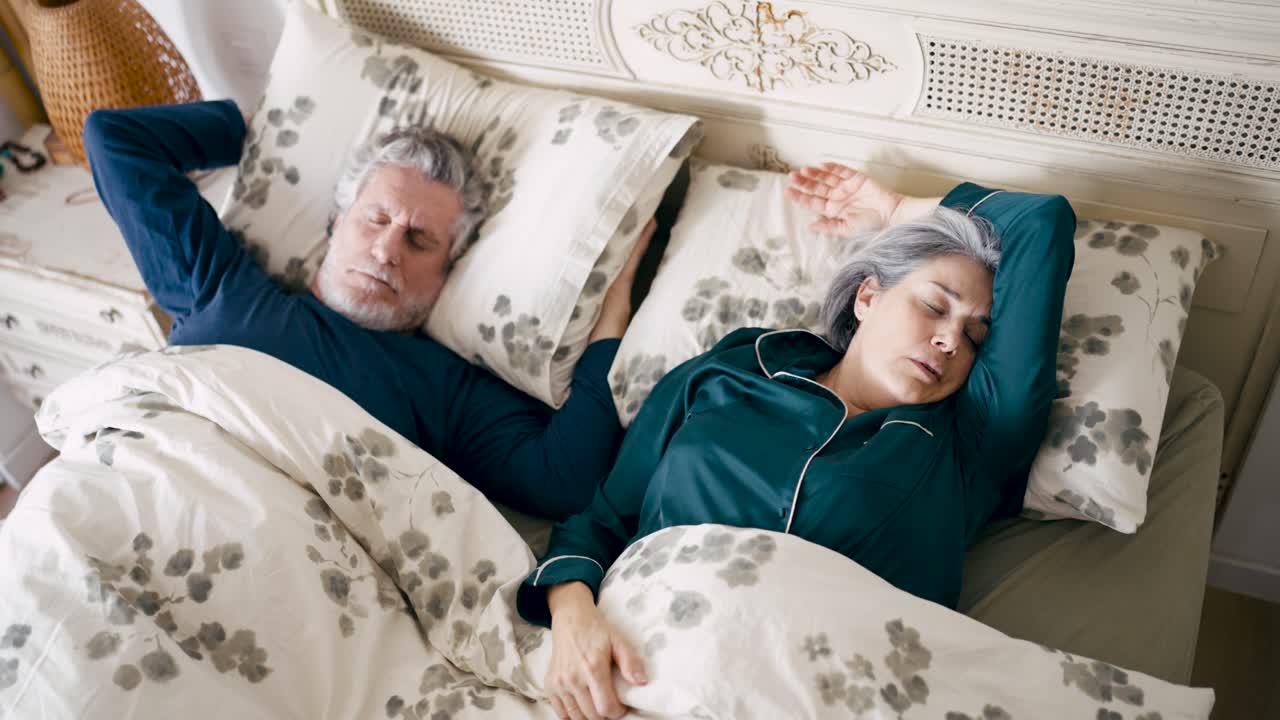 Mature Couple Sleeping in Bed, Man Disturbed by Snoring