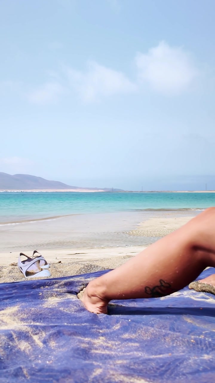 Woman's hand shaking sand off a towel at Risco beach
