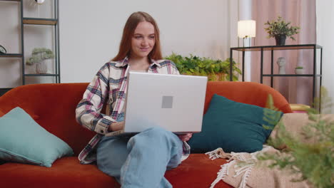 Caucasian-young-woman-sitting-on-sofa-closing-laptop-pc-after-work-online-in-living-room-at-home