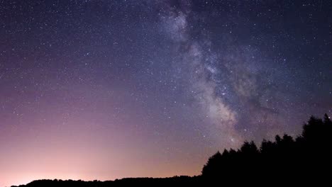 time lapse of the milky way with silhouette of ridge-line and trees