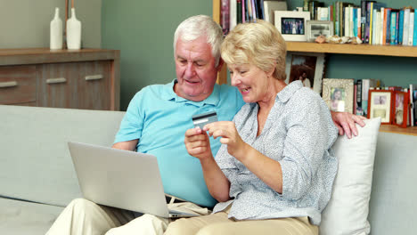 pareja de ancianos usando una computadora portátil y una tarjeta de crédito