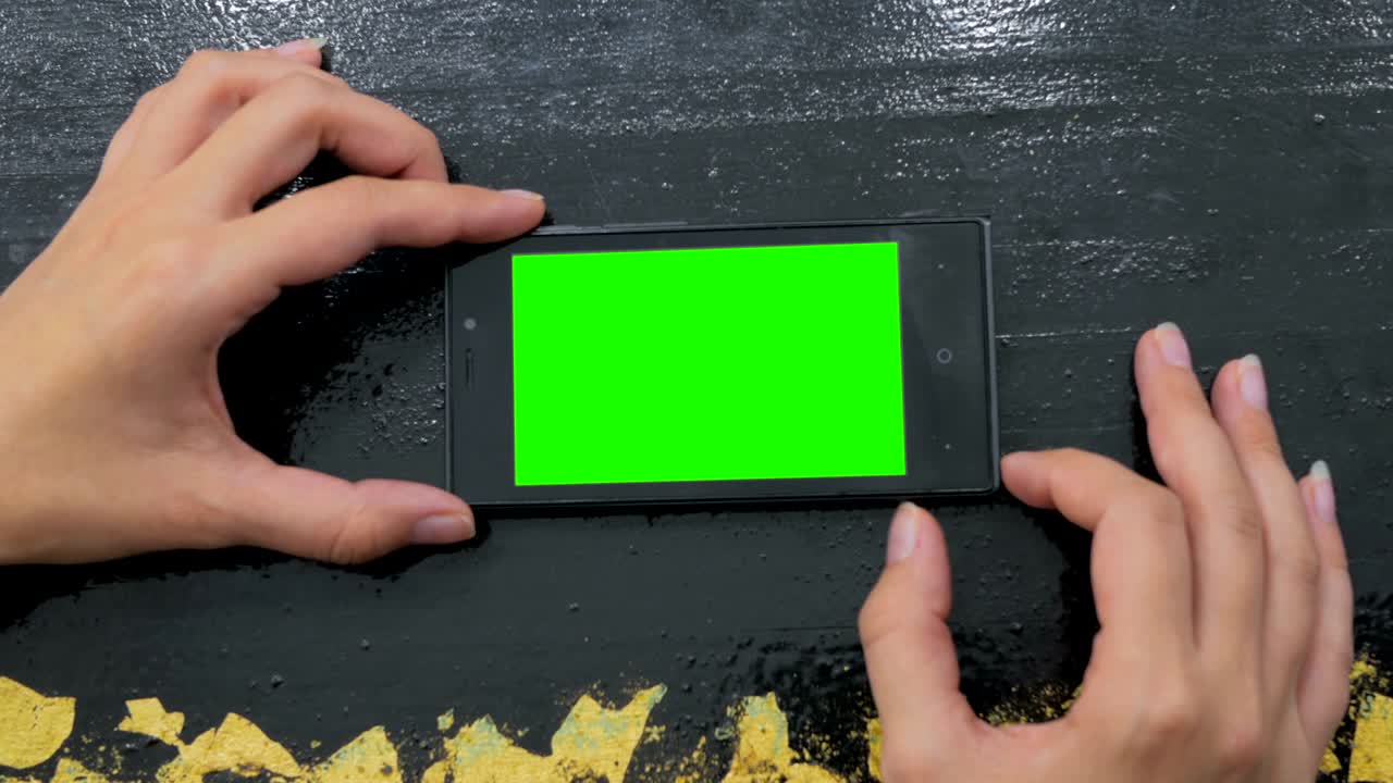 초록색 화면 을 가진 스마트폰 을 보고 있는 여자