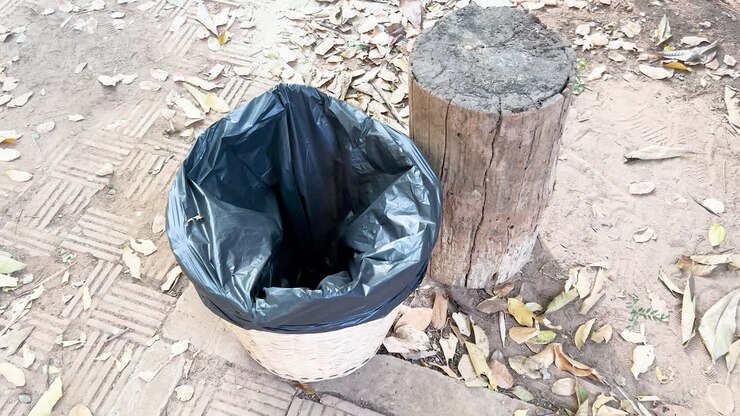 Persona che getta una bottiglia in un cestino esterno