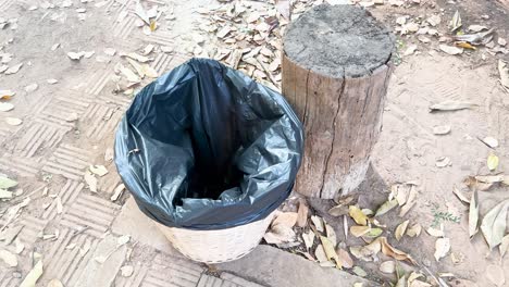 person discards bottle in outdoor trash bin