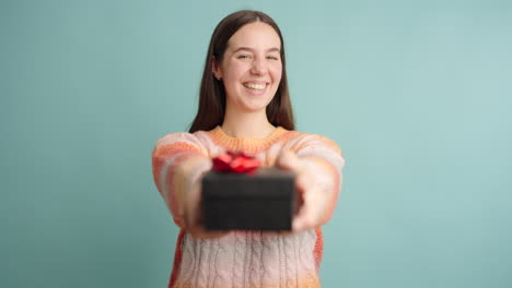 young woman offering a gift on turquoise background