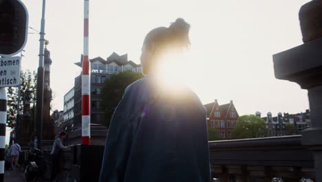 woman walking on a city bridge at sunset in amsterdam