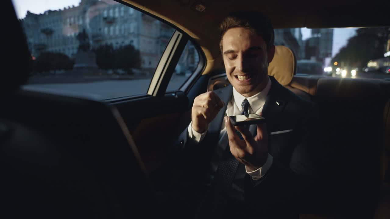 hombre de negocios enojado maldiciendo en una charla de voz en el teléfono móvil en un coche oscuro.