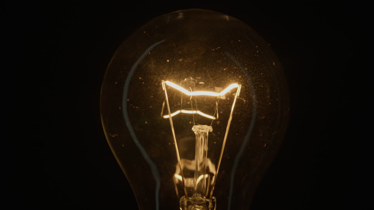 Fine glowing thread brightens inside vintage light on isolated dark surface