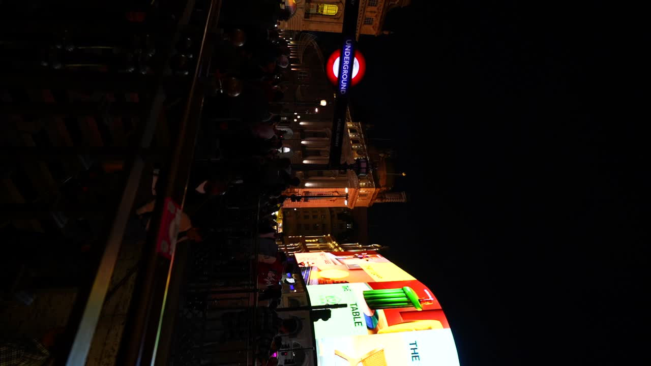 Night scene in London with people and illuminated signs