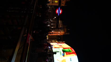 night scene in london with people and illuminated signs