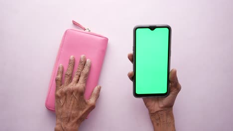 billetera rosa y teléfono inteligente en manos de ancianos