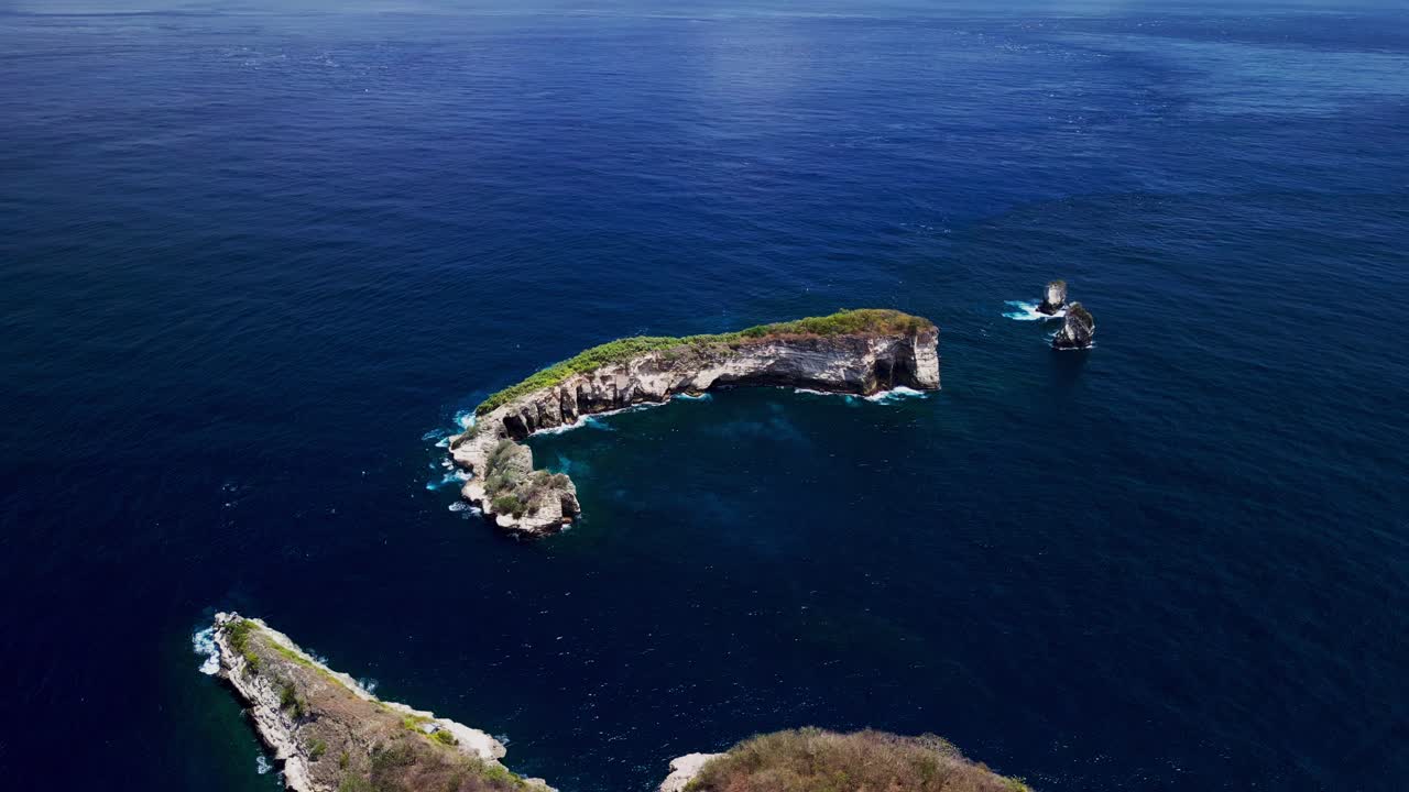 A small island floats in the middle of the deep blue sea with vibrant greenery and crystal clear waves washing its shores a perfect example of natural beauty and ocean serenity.