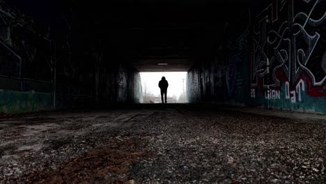 Silhouette-of-a-man-walking-in-dark-tunnel-towards-the-camera