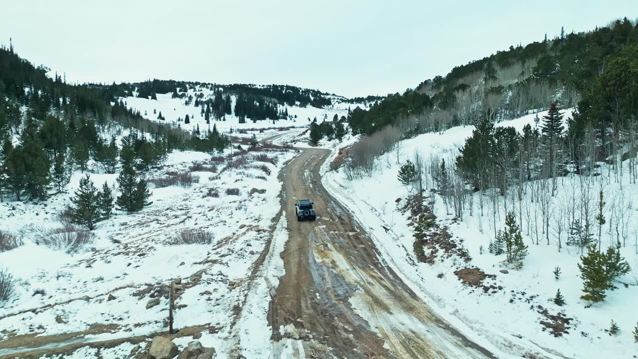 Aerial of SUV navigating snowy roads in Caribou Colorado ghost town, eerie abandoned settlement in the mountains