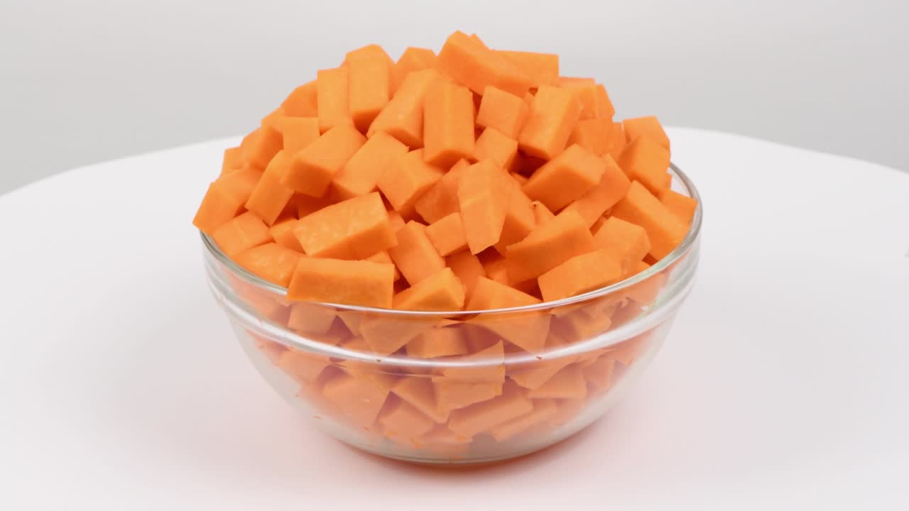 calabaza cortada en rodajas en un cuenco de vidrio (cucurbita moschata, calabaza de calabaza o grama de guitarra) aislada en blanco. vista lateral. movimiento de bucle. rotación 360.