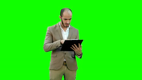 concentrated businessman reading financial report on a green screen, chroma key