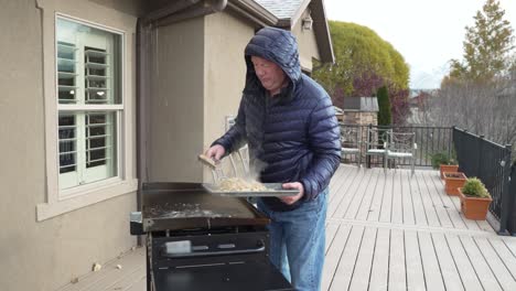 el hombre recoge huevos de campamento y hachís después de cocinarlos en la plancha superior plana