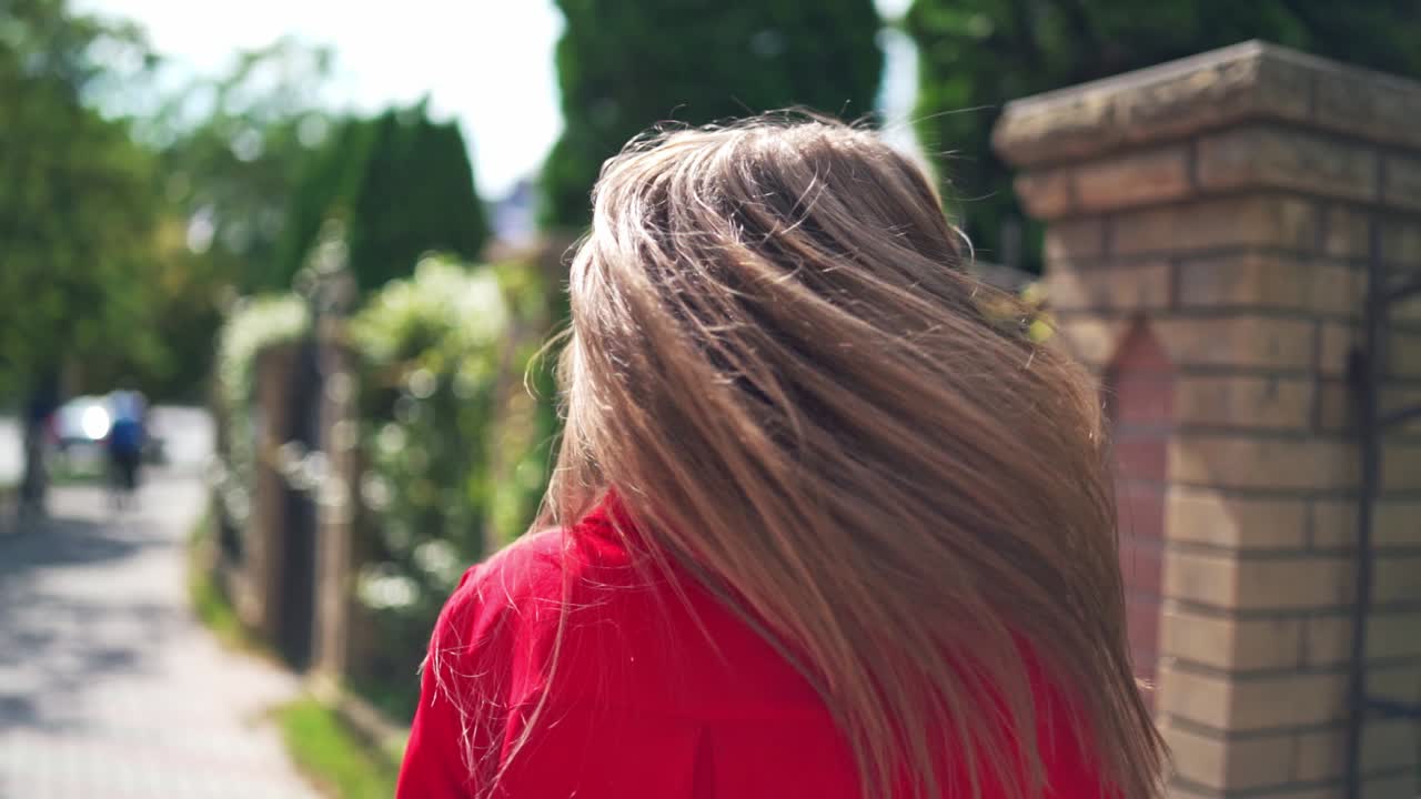 Portrait of attractive young female in summer. Beautiful woman with long hair turning around herself happily. Pretty woman walking along the street.