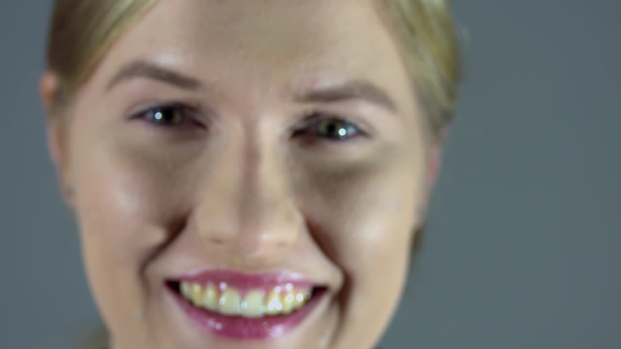 Closeup on the face of a smiling blond woman. From out of focuse to focuse