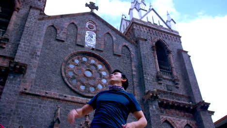 Ground-view-of-young-man-by-church-at-Baños-de-Agua-Santa,-Ecuador