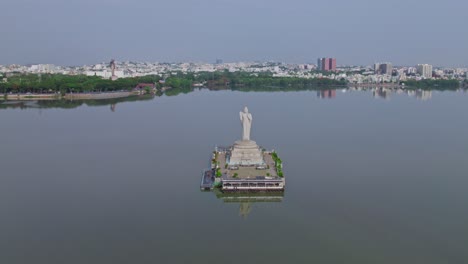 buddha statue, ambedkar statue with buildings reflections on hussain sagar lake at tank bund, khairtabad, hyderabad, telangana, india. day time, moving down, drone shot, 4k.