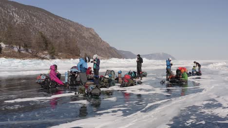 a circular flight around a group of tourists sitting on the rest after a long skating on the ice lake baikal in winter.