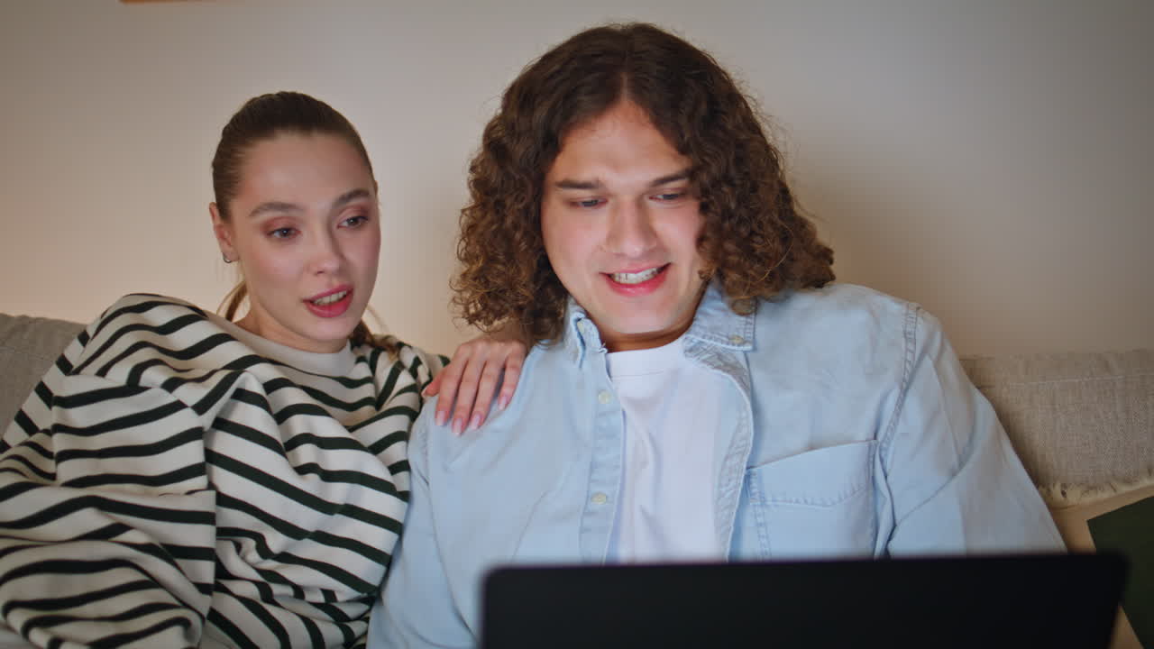 Couple discussing laptop content relaxing together at cozy home sofa closeup
