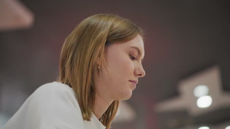 side profile of young woman concentrating on work in modern indoor environment with blurred abstract background lighting, conveying focus, productivity, and professional atmosphere