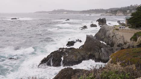 rough ocean water hitting rocks in monterey bay california - heavy waves in distance