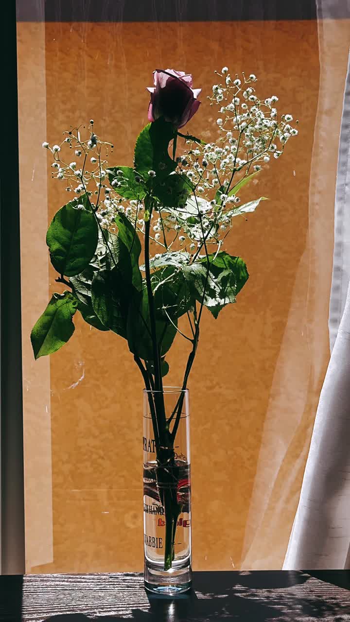 un ramo de rosas y gipsófila en un jarrón junto a la ventana