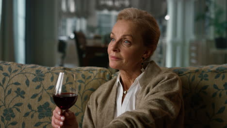 Portrait-pensive-elderly-woman-enjoying-red-wine-glass-at-home.-Old-aged-lady