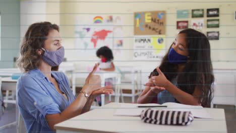 School-concept-icons-over-female-teacher-talking-in-sign-language-with-a-girl-at-elementary-school